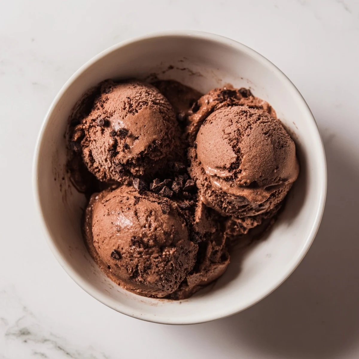 Homemade chocolate sourdough ice cream being scooped from a vintage container showing its rich fudge texture