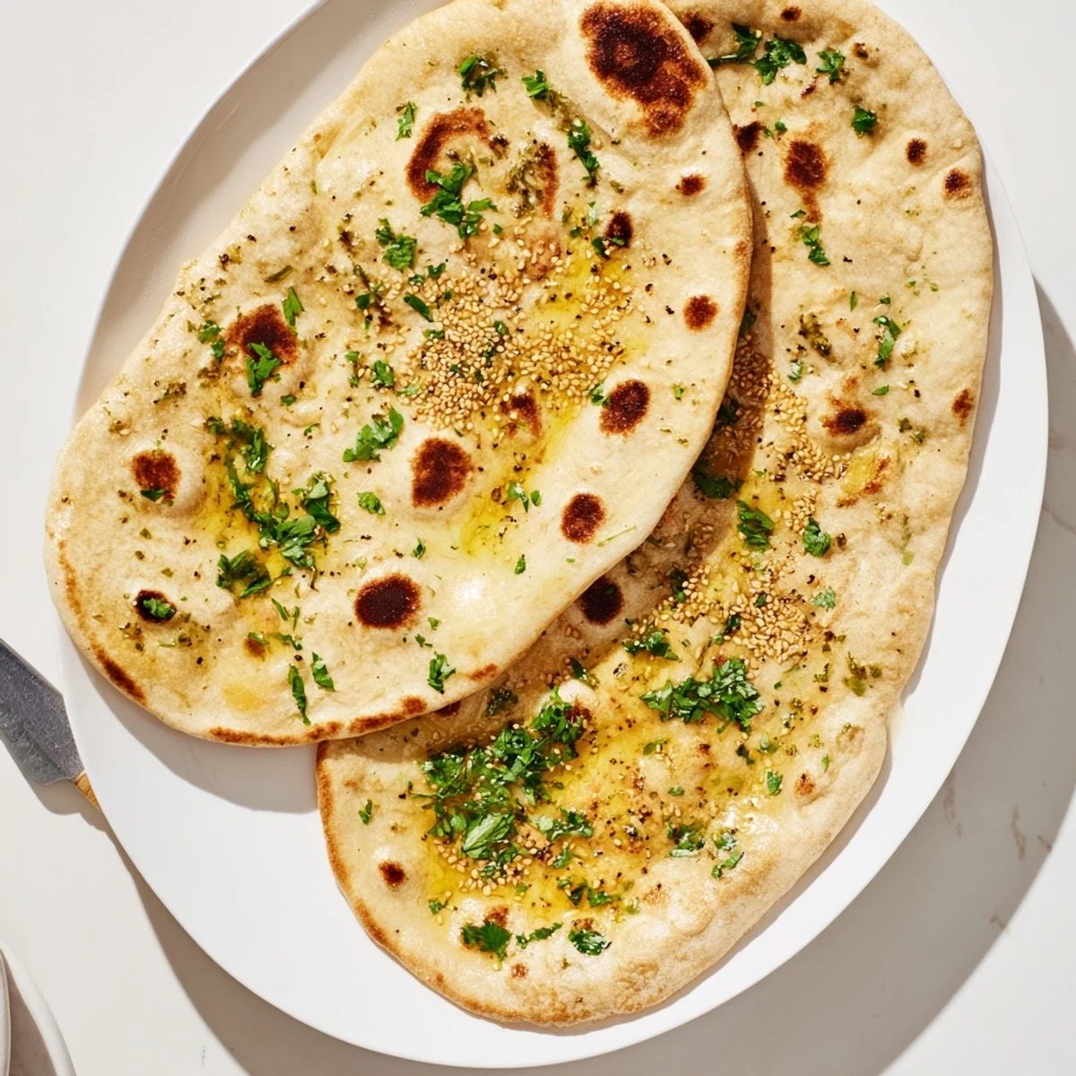 Pillowy homemade naan bread made with sourdough discard resting on a wooden board