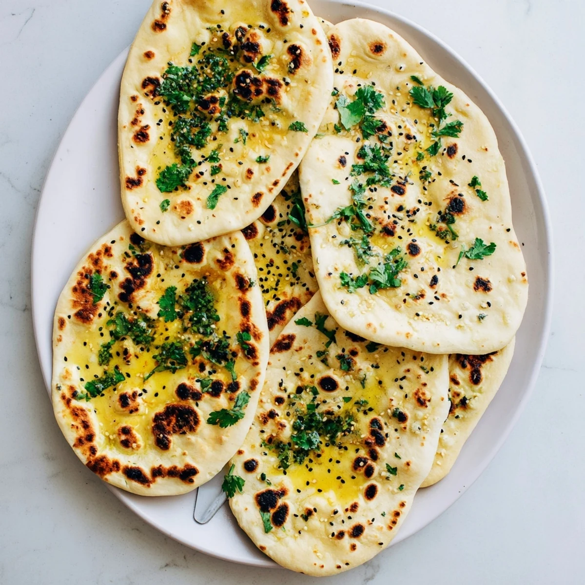 Warm soft naan with golden char marks served alongside curry in a white bowl