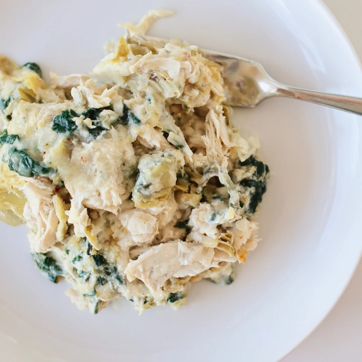 Hearty Spinach Artichoke Chicken Casserole sliced, creamy interior with tender chicken chunks
