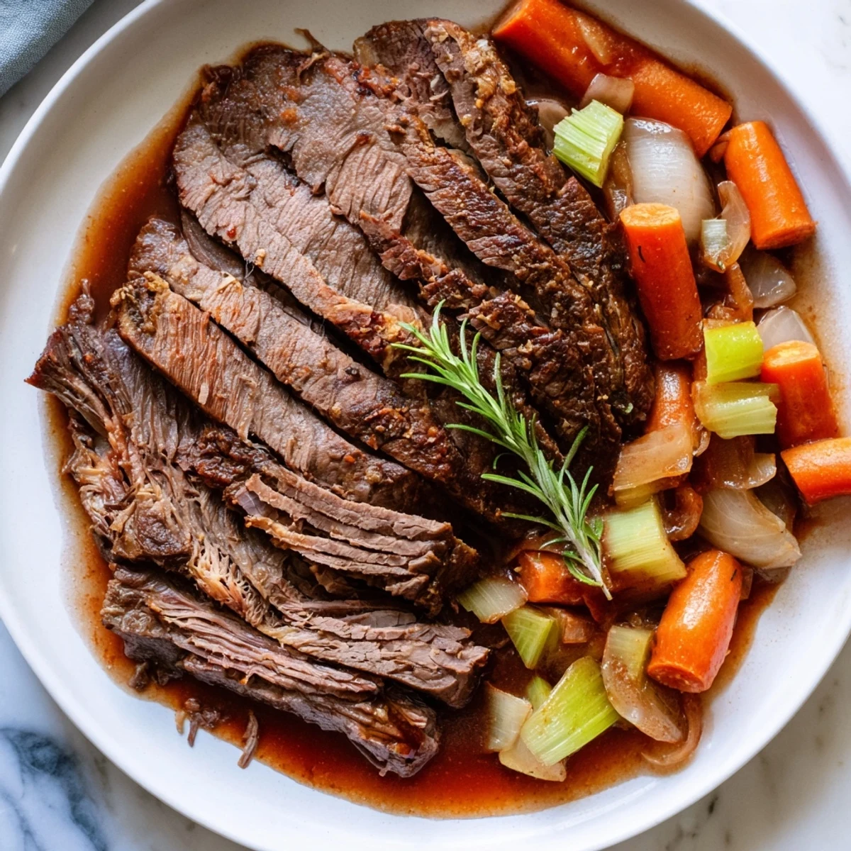 Fall-apart perfect pot roast garnished with fresh rosemary and served steaming hot